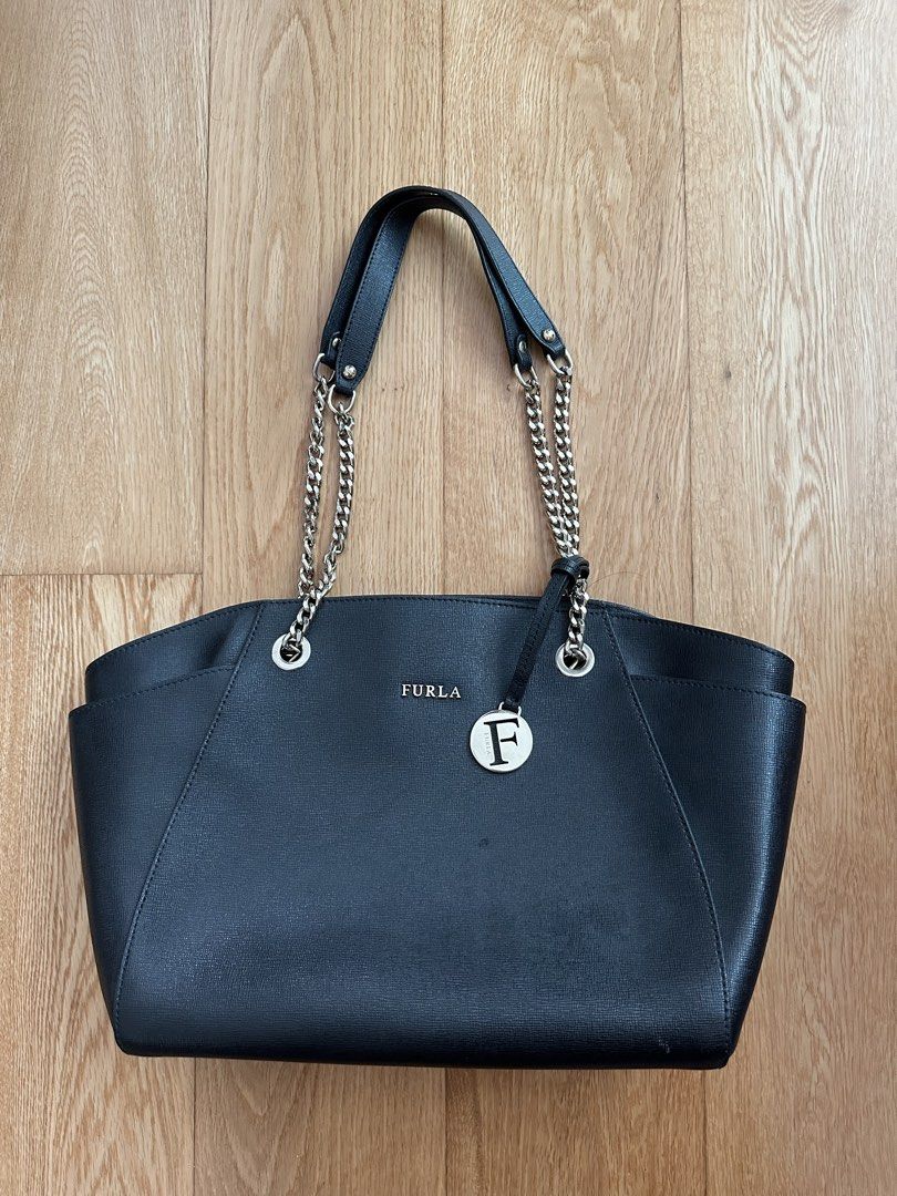 Furla Black Tote Bag with Chain Straps (Category: Luxury Bags & Wallets) located in Quezon City. Submitted by patscloset8 (Listing ID 1431574741, Image 1). Description: - Furla black tote bag - Chain straps - Magnetic closure - Spacious interior - Fabric lining with Furla logo - Interior pockets for organization - Brand new being sold at 380 USD (around 20,000 pesos) From the website: Material: Saffiano genuine leather Dimensions/Measurements: He