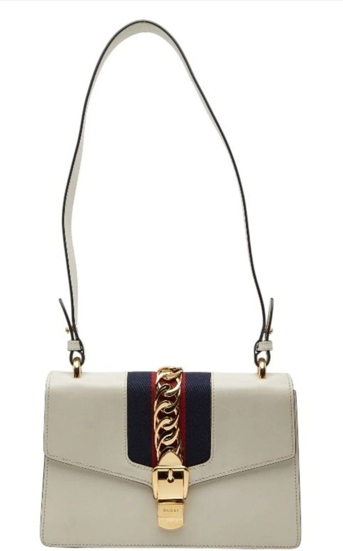 Gucci Sylvie Leather Shoulder Bag (Category: Luxury Bags & Wallets) located in Caloocan City. Submitted by mariahcara (Listing ID 1431581665, Image 1). Description: - Gucci Sylvie shoulder bag off-white colored leather - with the navy and red web stripe, and gold-tone buckle and chain accent - Includes white leather shoulder strap; gold chain strap not included - this is super mini in size -has a vintage vibes and perf to complete blue or white d