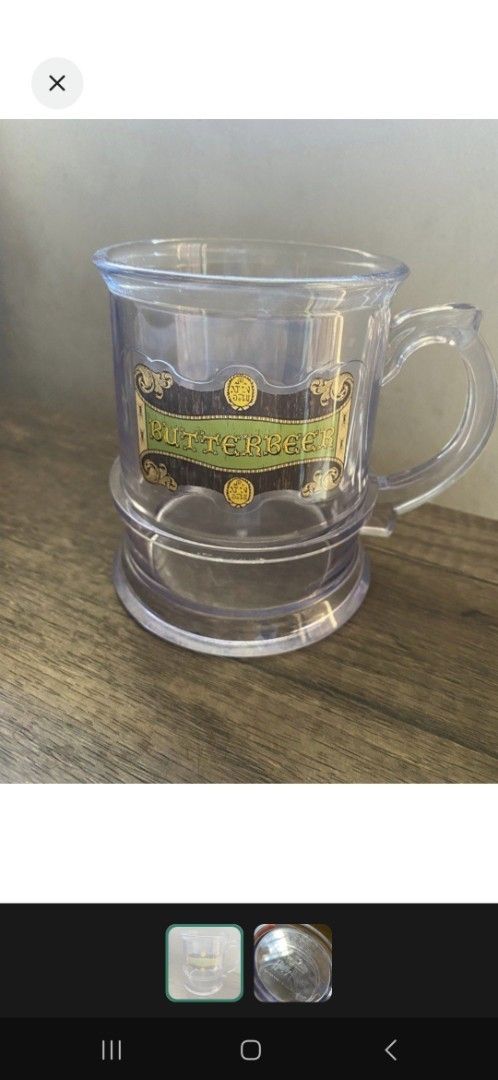 Harry Potter Universal Studios Butterbeer Mug (Category: Coffee & Tea Tableware) located in Valenzuela. Submitted by winssian (Listing ID 1431794152, Image 1). Description: - Clear plastic mug - Features Butterbeer label - Includes handle and base - Marked with Universal Studios logo Displayed only.