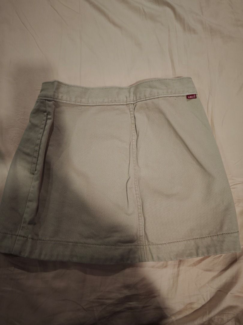 Levi's Skirt (Category: Skirts) located in Quezon City. Submitted by declutteringmami (Listing ID 1431665637, Image 2). Description: - Levi's skirt - Light beige color - Wrap-style front with two buttons - Levi's logo tag at the back - Size: W25 - Made of sturdy fabric - Classic and versatile design - Ideal for casual wear -Never used -Missing one button.