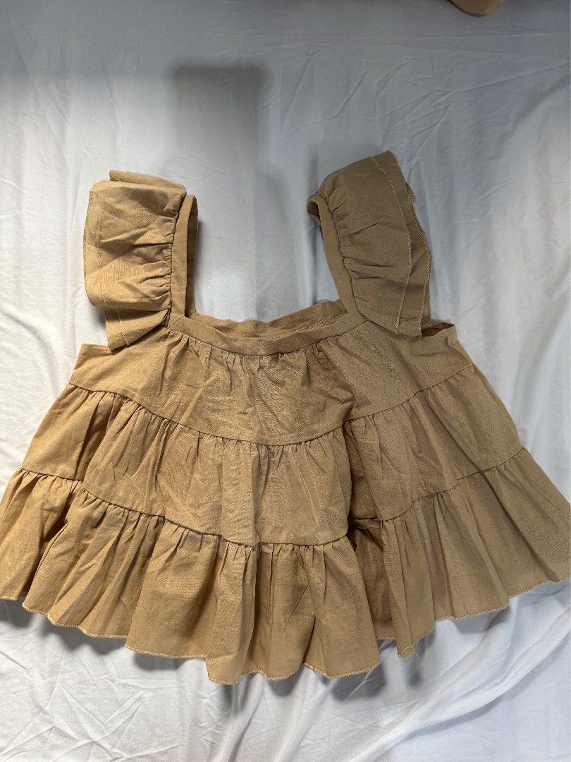 Shein Off-Shoulder Ruffle Top (Category: Blouses) located in Manila. Submitted by raphaelain17296 (Listing ID 1431734972, Image 2). Description: - Shein off-shoulder top - Beige color - Size: L - Design: Layered ruffles - Sleeves: Short - Origin: Made in China.
