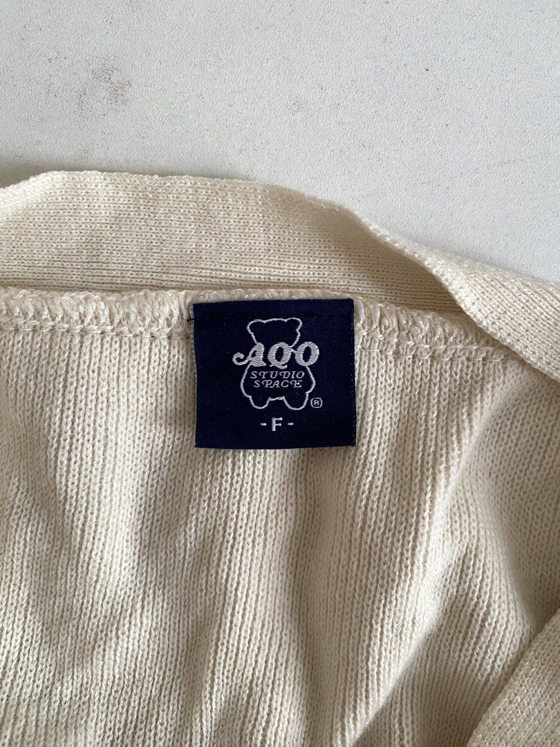 AQO Studio Space Cream Cardigan (Category: Coats, Jackets and Outerwear) located in Manila. Submitted by lomlberries (Listing ID 1431893580, Image 2). Description: - Cream-colored cardigan from AQO Studio Space - Features a bear logo on the chest - Two front pockets - Button-up closure with an orange button - Size: F - Condition: Good.