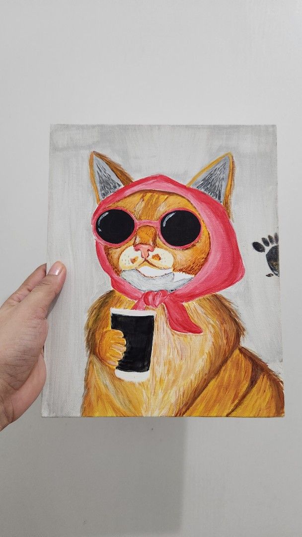 Cat Painting with Red Hood (Category: Art & Prints) located in Cavite. Submitted by joycreates (Listing ID 1431852230, Image 1). Description: - Original artwork - Features a cat wearing a red hood - Cat has orange fur and large black eyes - Cat is holding a black object - Painted on a square canvas - Light grey background -25x20cm.