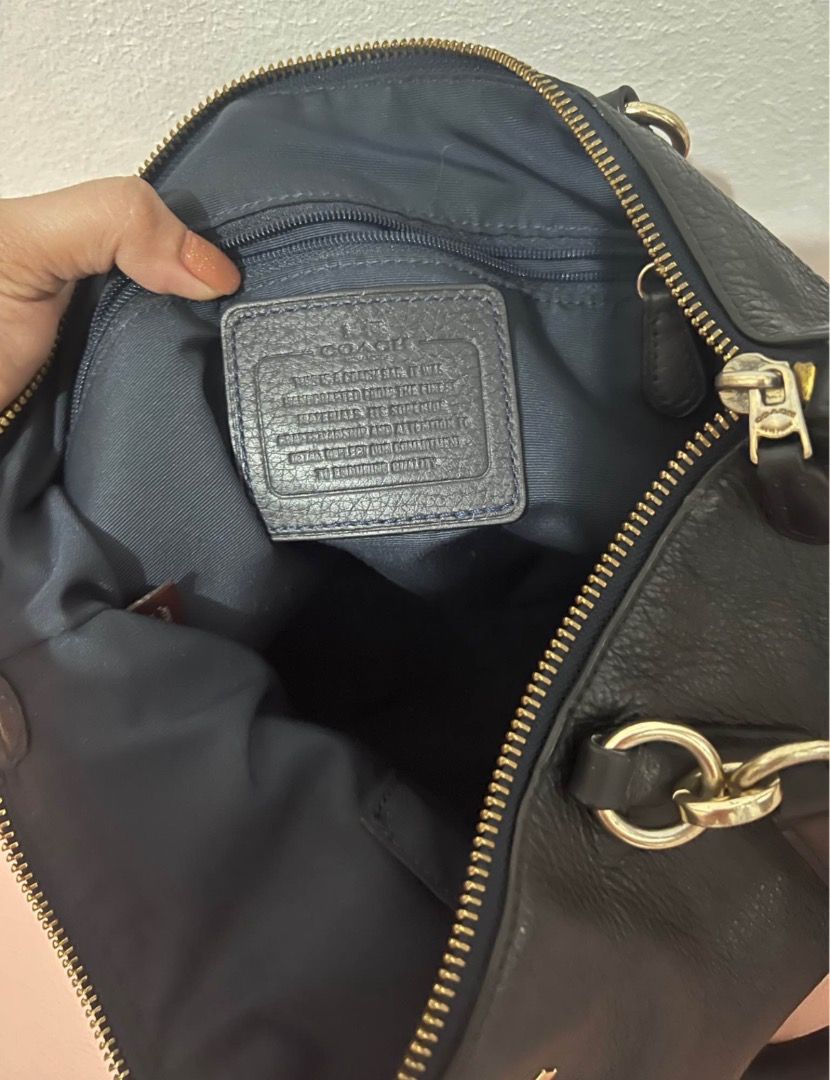 Coach Black Leather Handbag (Category: Luxury Bags & Wallets) located in Quezon City. Submitted by shop8holic (Listing ID 1431816275, Image 3). Description: - Black Coach handbag - Gold-tone hardware - Zip closure - Dual top handles - Detachable shoulder strap - Textured leather - Dark blue fabric lining - Includes Coach leather tag.