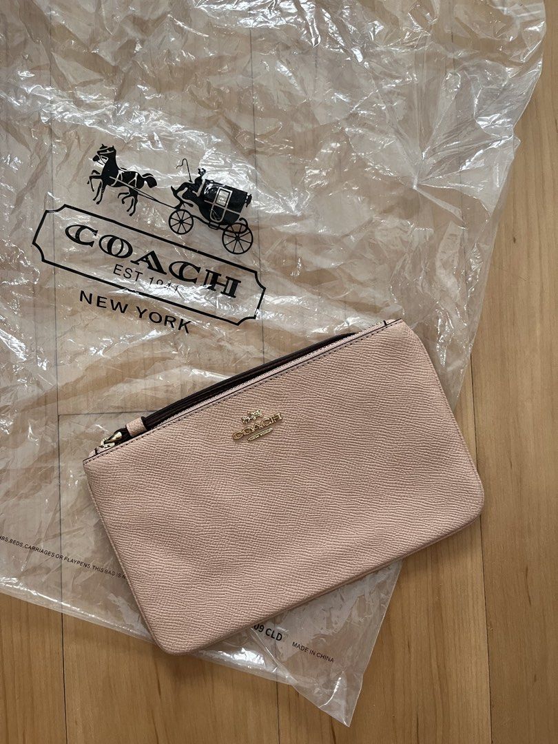 Coach Wristlet Clutch (Category: Luxury Bags & Wallets) located in Caloocan City. Submitted by nikkibril07480 (Listing ID 1431829300, Image 1). Description: - Stylish Coach wristlet clutch - Light pink exterior - Gold-tone Coach logo - Secure zipper closure - Comes with original Coach plastic bag RFS: Decluttering .