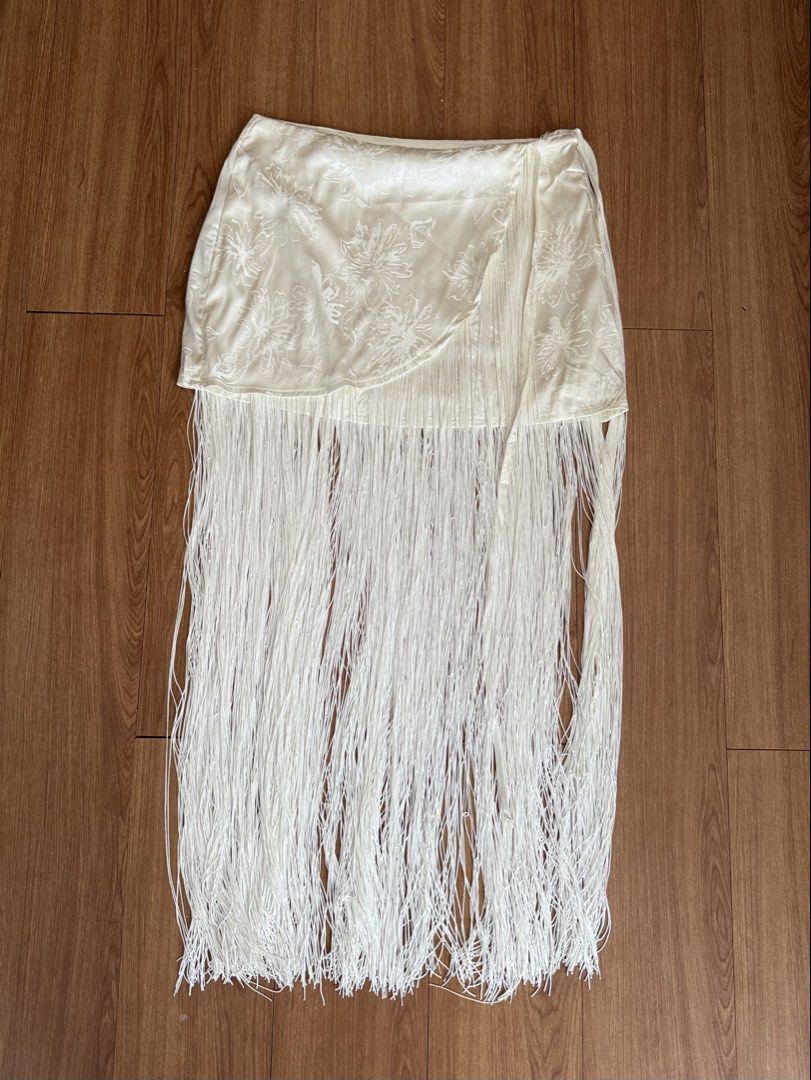 Cream Fringe Wrap Skirt (Category: Skirts) located in Muntinlupa City. Submitted by stephschrber (Listing ID 1431835962, Image 2). Description: - Cream-colored wrap skirt - Fringe detailing - Wrap design with tie closure - Subtle fabric pattern.