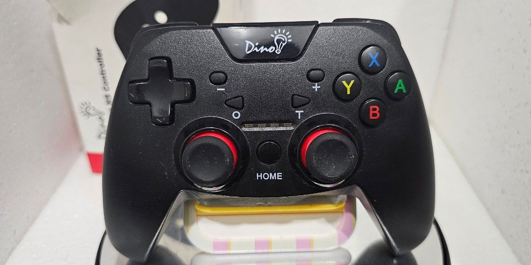 Dino NS Wireless Controller (Category: Controllers) located in Baguio. Submitted by bitsbaguio (Listing ID 1431806397, Image 2). Description: - Black Duoqi wireless controller for Nintendo Switch, PC, PS3 - Includes original box - Features buttons and joysticks - Comes with a rotating display stand - Stand has an on/off switch - Never used.