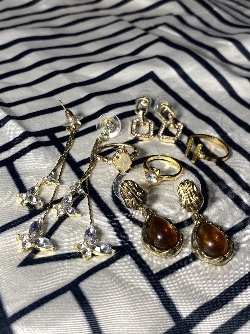 Gold-toned Earrings and Rings Set (Category: Earrings) located in Taguig. Submitted by _rosiesells (Listing ID 1431965472, Image 1). Description: Gold-toned earring and ring set. Includes square and teardrop earrings, plus rings with various designs, including a butterfly and a clear stone..