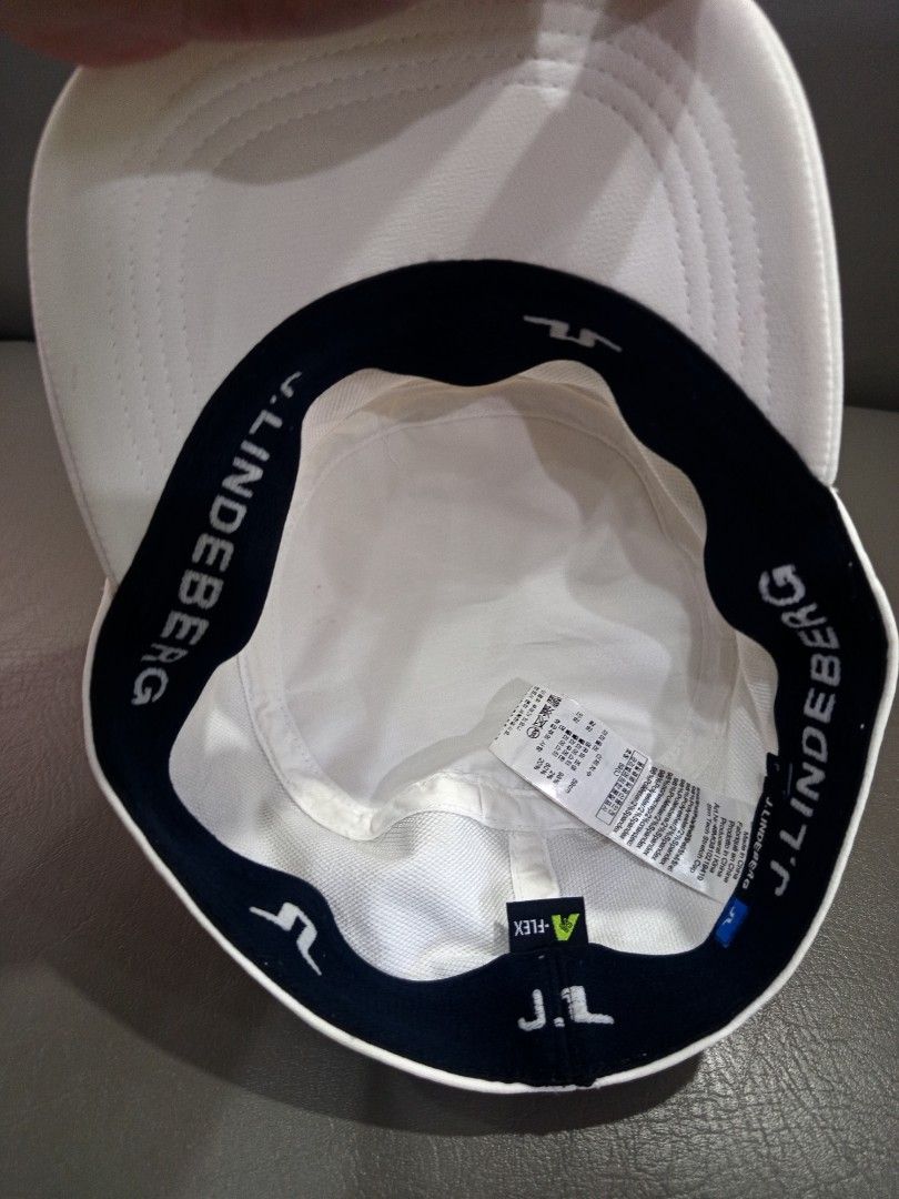 J. Lindeberg White Cap (Category: Caps & Hats) located in Davao. Submitted by vaness041421 (Listing ID 1431961413, Image 3). Description: - J. Lindeberg white cap - Features a flat brim and structured crown - Brand logo on the side - Interior lining with brand name - Made of smooth, possibly synthetic material - Clean, minimalist design.
