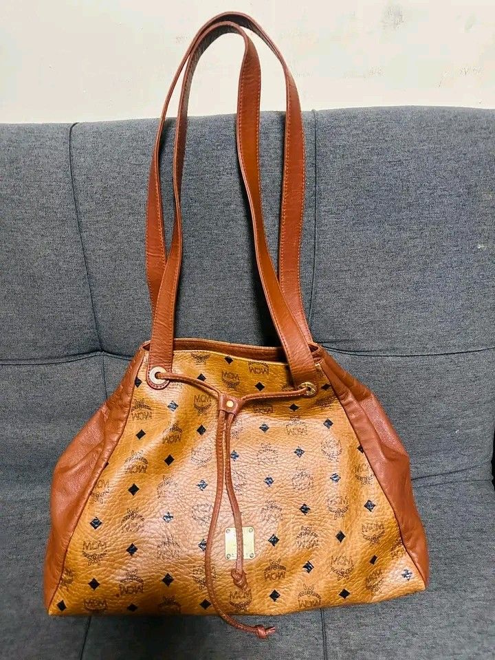 MCM long handle shoppers Bag (Category: Luxury Bags & Wallets) located in Bulacan. Submitted by alfredcarp0905 (Listing ID 1431948443, Image 1). Description: - Authentic MCM tote bag - Drawstring closure - Brown leather handle and trim - Features the classic MCM logo pattern - Yellow interior - Swiss-made zipper.
