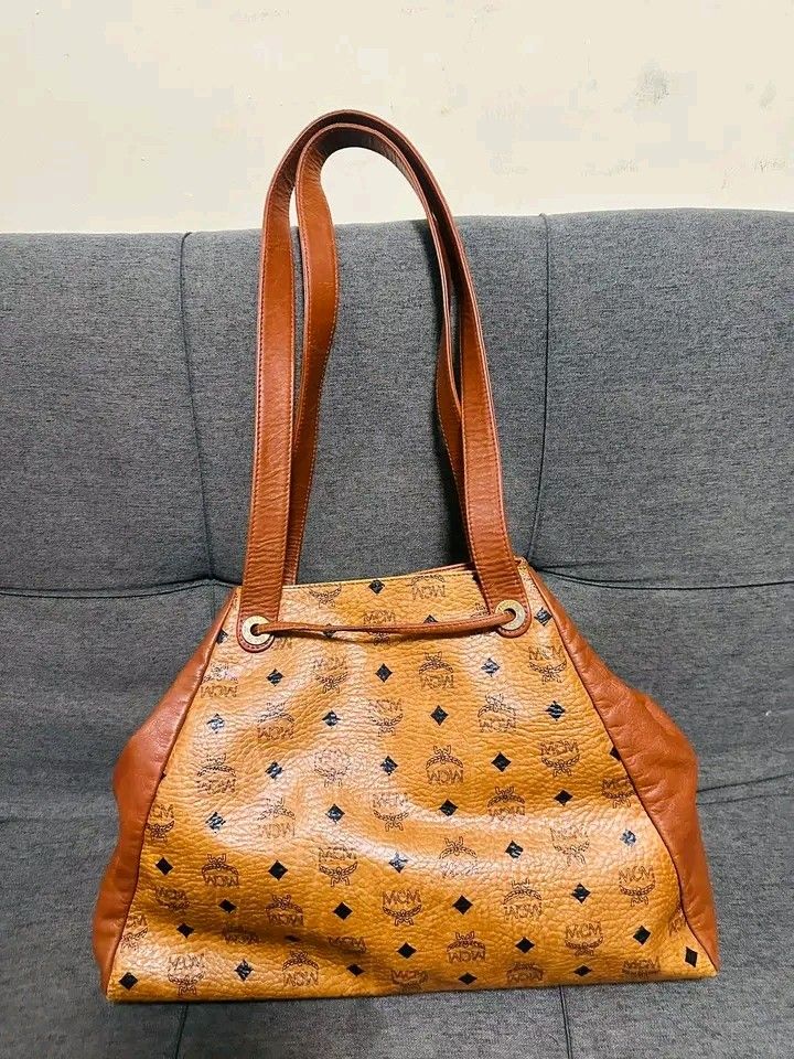 MCM long handle shoppers Bag (Category: Luxury Bags & Wallets) located in Bulacan. Submitted by alfredcarp0905 (Listing ID 1431948443, Image 2). Description: - Authentic MCM tote bag - Drawstring closure - Brown leather handle and trim - Features the classic MCM logo pattern - Yellow interior - Swiss-made zipper.