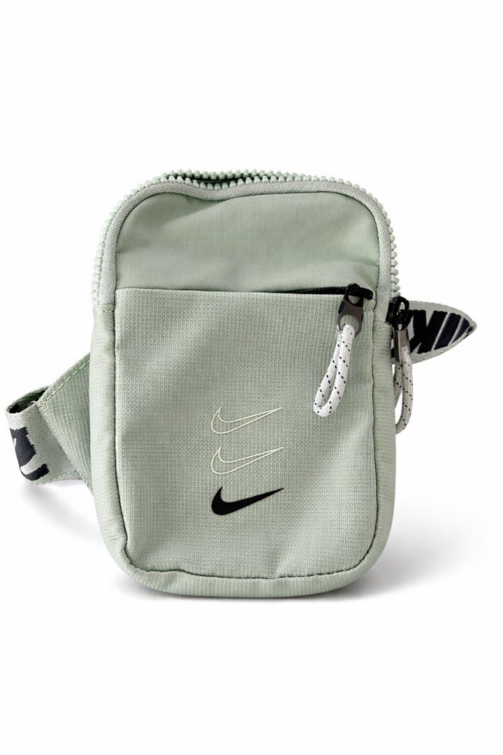 Nike Heritage Crossbody Bag (Category: Cross-body Bags) located in Antipolo. Submitted by cl026 (Listing ID 1431820836, Image 2). Description: - Nike Heritage Crossbody Bag - Mint green color - Full strap length 53" -SIZE: L6.5" x W4.5" - Repeating Nike logo on strap - Small, rectangular shape - Zippered main compartment - Smaller front pocket - Nike logo on front - Adjustable crossbody/shoulder strap.