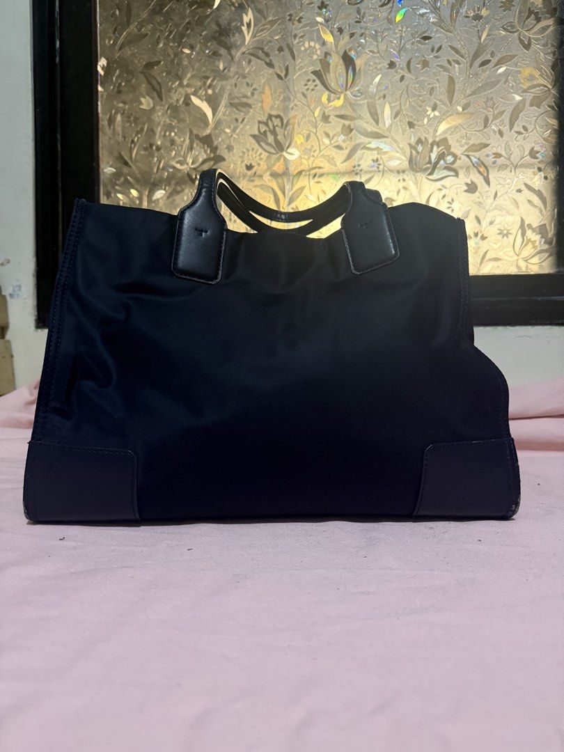 Tory Burch Ella Tote Bag (Category: Luxury Bags & Wallets) located in Pasig City. Submitted by help.a.hoarder.out (Listing ID 1431996814, Image 3). Description: - Tory Burch Ella tote bag - Color: Navy blue - Features embossed logo - Leather handles - Magnetic fastening - Spacious interior - Zippered pocket - Shows wear on corners and needs repainting - Worn out due to daily use at school - Negotiable.
