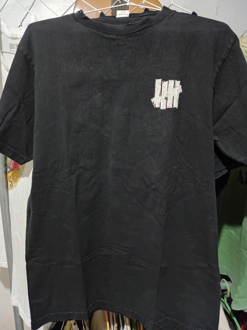 Undefeated Graphic Tee (Category: Tshirts & Polo Shirts ) located in Quezon City. Submitted by reddcluttermnl (Listing ID 1431884236, Image 1). Description: - Undefeated t-shirt - Color: Black - Graphic on the back featuring a soccer ball and the word "Undefeated" - Small Undefeated logo on the front.