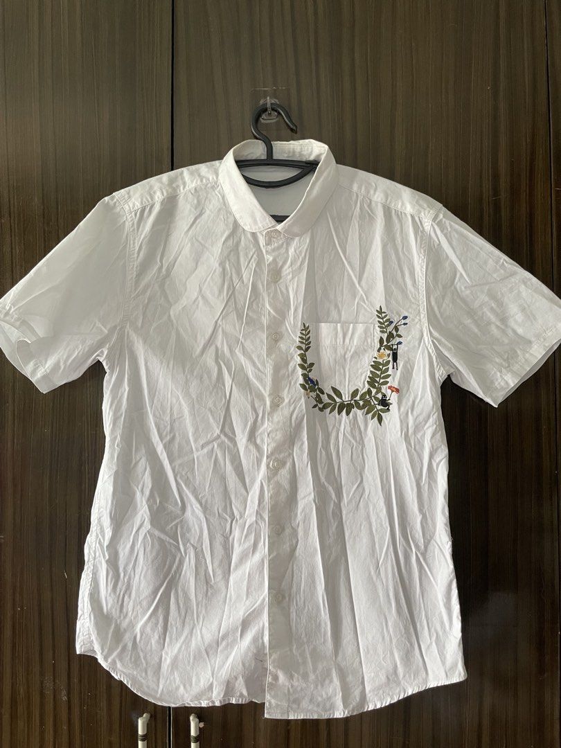Embroidered White Short Sleeve Shirt (Category: Shirts) located in Antipolo. Submitted by misalrad (Listing ID 1432035915, Image 1). Description: - White short sleeve shirt - Embroidered chest pocket with leaves, flowers, and figures - Button-down front - Classic collar - Perfect for casual wear.