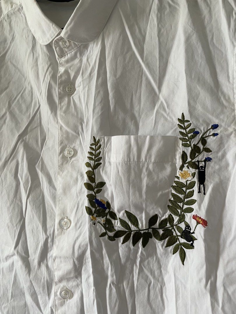 Embroidered White Short Sleeve Shirt (Category: Shirts) located in Antipolo. Submitted by misalrad (Listing ID 1432035915, Image 2). Description: - White short sleeve shirt - Embroidered chest pocket with leaves, flowers, and figures - Button-down front - Classic collar - Perfect for casual wear.