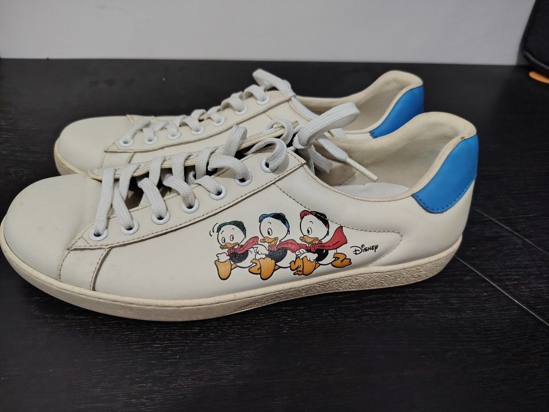 Gucci Donald Duck Sneakers (Category: Sneakers) located in Angeles City. Submitted by daruwinoru7 (Listing ID 1432166904, Image 1). Description: - Gucci Donald Duck Sneakers - White leather upper - Blue heel tab - Donald Duck graphic on the side - Gucci branding on heel and insole - Signs of wear on soles - Size visible on insole - White laces.