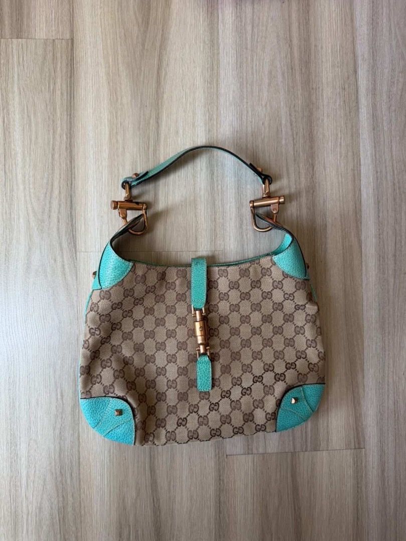 Gucci Jackie Piston Lock Hobo Bag (Category: Luxury Bags & Wallets) located in Taguig. Submitted by imeverywhereimsellahhhh (Listing ID 1432120942, Image 1). Description: - Authentic Gucci Jackie Hobo bag - Iconic GG canvas - Turquoise leather accents - Bamboo clasp - Single handle - Spacious interior - Hardware shows wear - Gucci logo visible.