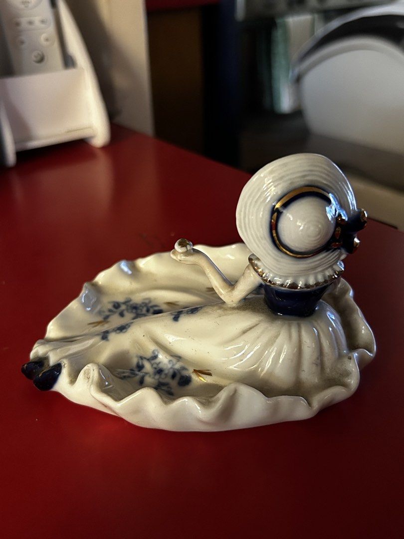 Vintage Lady Figurine Trinket Dish (Category: Other Home Decor) located in Las Pinas. Submitted by rjmwings (Listing ID 1432136504, Image 2). Description: Vintage figurine features a lady in a dress, serving as a trinket dish. Bought in 2002. Made in Indonesia. The figurine is white with blue floral accents and gold detailing. The lady is wearing a hat and has a blue collar. The dish has a ruffled edge. It is a decorative piece that can hold smal
