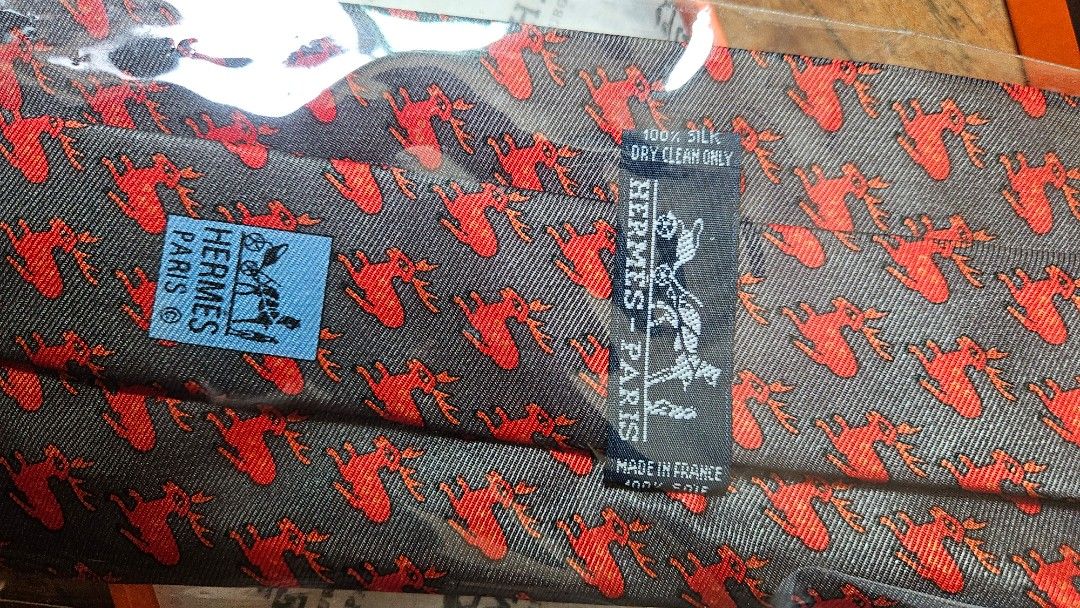Hermès Vintage Silk Tie (Category: Ties) located in San Juan City. Submitted by paocastee (Listing ID 1432211117, Image 3). Description: Authentic Hermès silk tie featuring a repeating red pattern on a gray background. The tie comes with its original orange box. Made in France. The tie is 100% silk and dry clean only. Never used. Price Negotiable Can inspect item if need .