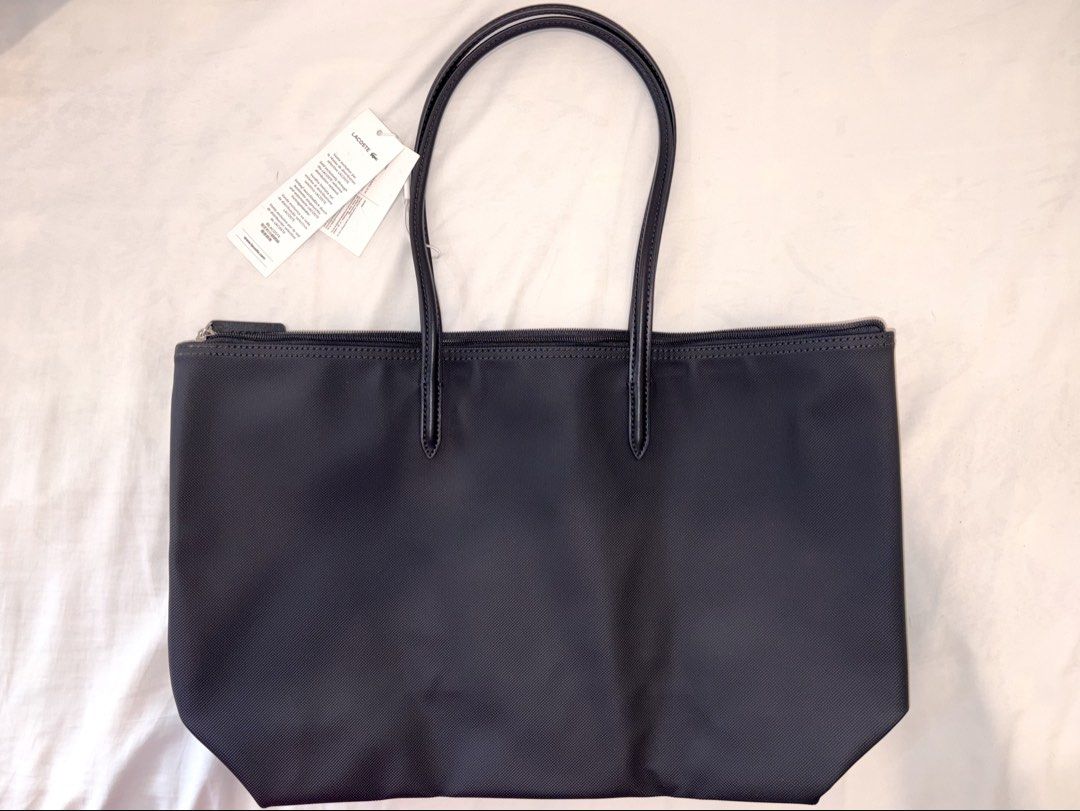 Lacoste Shoulder Tote Shopping Bag (Category: Shoulder Bags) located in Paranaque City. Submitted by ymrtn (Listing ID 1432290857, Image 2). Description: 100% PVC Long handle Dimensions L18 x W12 × D5 in - Embroidered Crocodile branding - Zippered - One interior net pocket with hook - Lacoste branded zipper slider RFS: received as a gift I already have.