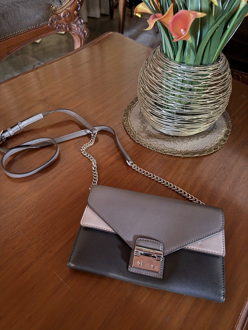 Michael Kors Clutch Bag (Category: Luxury Bags & Wallets) located in Lubao. Submitted by xpatriziam (Listing ID 1432282491, Image 1). Description: - Michael Kors clutch bag - Multi-tone design (gray, beige, black) - Silver chain strap - Secure clasp closure - Interior: multiple compartments, zippered pocket - Perfect for essentials - Elegant and stylish.