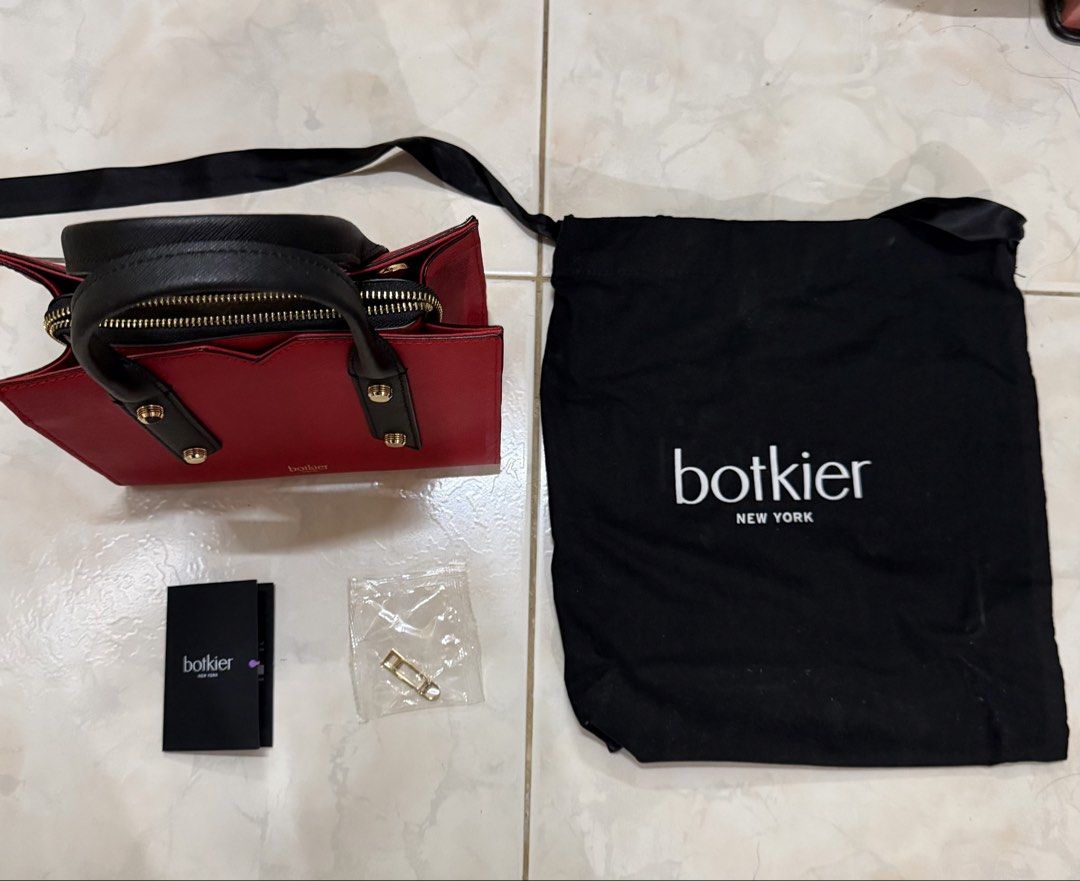 Botkier New York Red Handbag (Category: Luxury Bags & Wallets) located in Makati City. Submitted by jhanski (Listing ID 1432537167, Image 1). Description: - Botkier New York handbag - Striking red color with black accents - Top handle design - Detachable strap included - Comes with dust bag - Gold-colored hardware - Interior zipper closure - Includes small gold-colored clasp and tag.