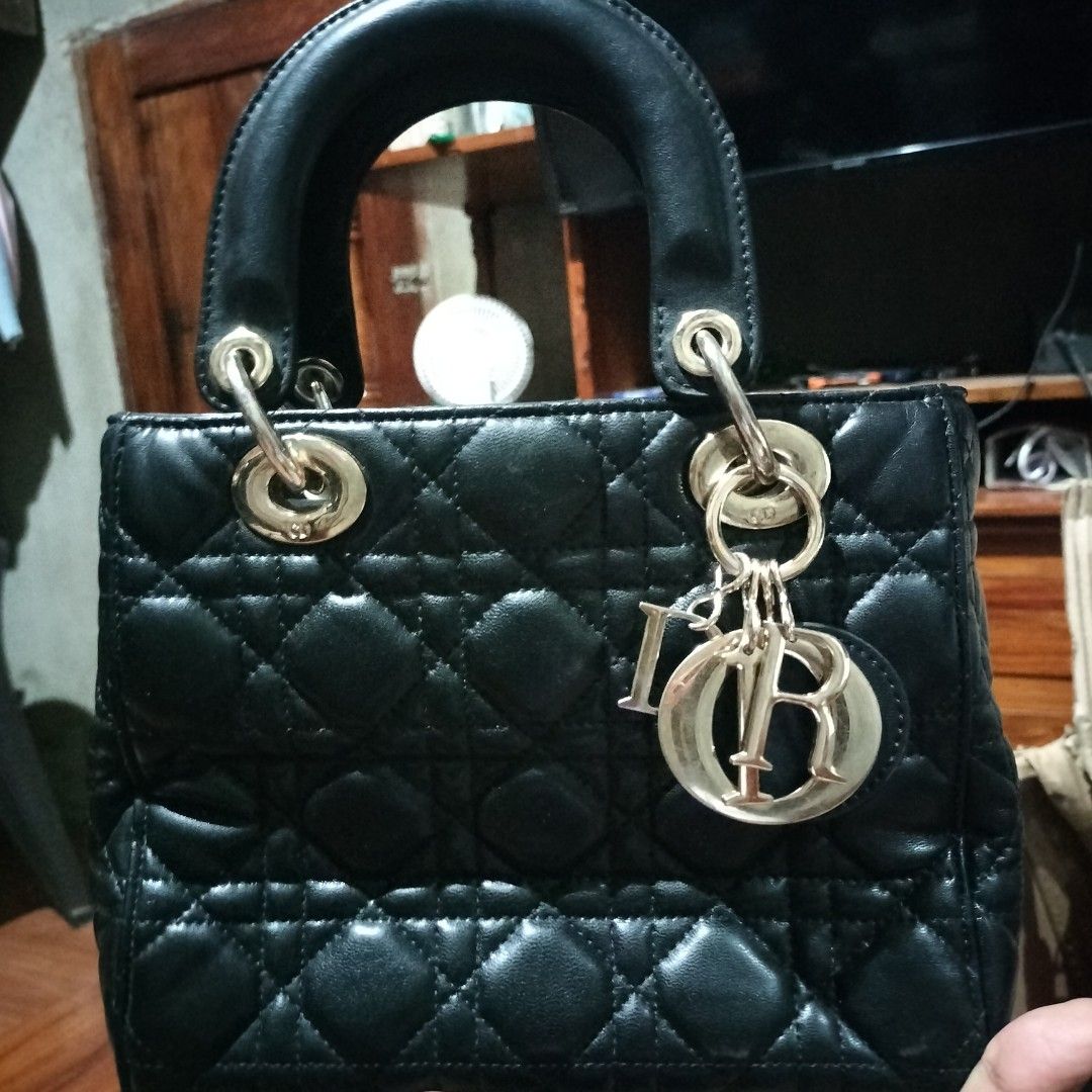 Christian Dior Lady Dior Handbag (Category: Luxury Bags & Wallets) located in Manila. Submitted by swifthawk-cfc412 (Listing ID 1432528209, Image 1). Description: Black Lady Dior handbag. Features a quilted design, top handles, and a detachable Dior charm. The interior includes a branded leather tag that reads "Christian Dior Paris Made in Italy". The serial number is 99-MA-0098. Includes metal feet on the bottom of the bag..