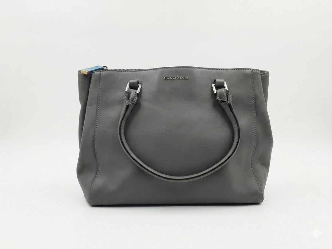 Coccinelle Grey Handbag (Category: Luxury Bags & Wallets) located in Quezon City. Submitted by thriftypieces (Listing ID 1432513469, Image 1). Description: - Grey Coccinelle 2 way bag (handbag and sling bag) but no sling - Top zipper closure - Dual top handles - Fabric lined interior with multiple compartments - Silver-tone hardware - Coccinelle logo on front, inside and cloth tag - Signs of wear: marks on exterior and strap, pen marks inside the
