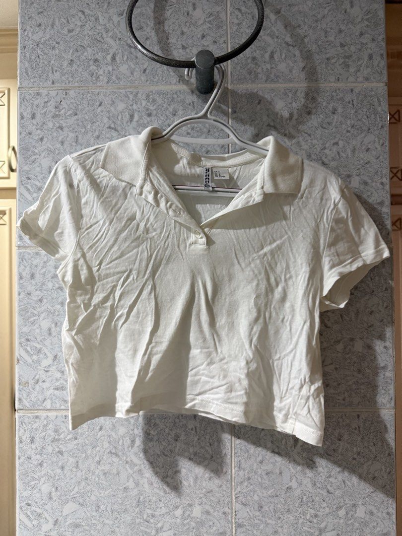 H&M Divided White Polo Shirt (Category: Shirts) located in Manila. Submitted by oceans18 (Listing ID 1432558802, Image 1). Description: H&M Divided white polo shirt, size M. Cropped style with collared neckline and short sleeves. Button-up front. Lightweight fabric. Great for casual wear..
