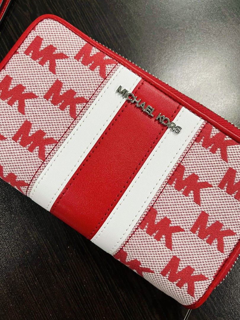 Michael Kors Red MK Print Wallet (Category: Wallets & Card holders) located in Pasig City. Submitted by stuffsnme (Listing ID 1432548516, Image 2). Description: - Michael Kors wallet with a striking red and white MK print. - Secure zip-around closure. - Convenient wrist strap for easy carrying. - Interior with multiple card slots and compartments for organization. - Features a stylish red leather stripe with the Michael Kors logo. - Includes the 
