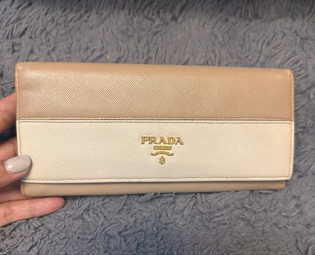 Prada Long Wallet (Category: Luxury Bags & Wallets) located in General Trias. Submitted by mimispreloves (Listing ID 1432557259, Image 1). Description: - Prada long wallet - Bi-color design: beige and cream - Multiple card slots - Compartments for organization - Zippered coin pocket - Made of leather - Prada logo on front - Snap closure - Gold-tone hardware -Php5k only .