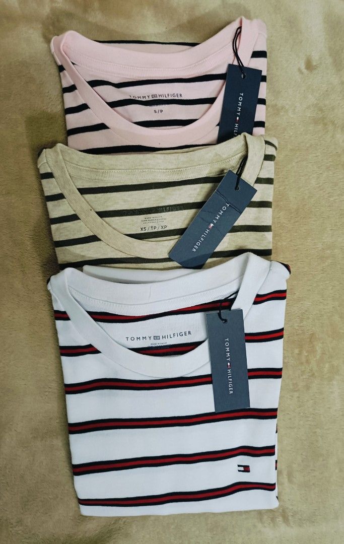 Tommy Hilfiger Striped T-shirts (Category: Tshirts & Polo Shirts ) located in Pasig City. Submitted by stuffsnme (Listing ID 1432545407, Image 1). Description: - Tommy Hilfiger striped T-shirts - Colors: Pink, Beige, White - Classic crew neck design - Features the Tommy Hilfiger logo - Brand new with tags attached - Sizes indicated on tags.
