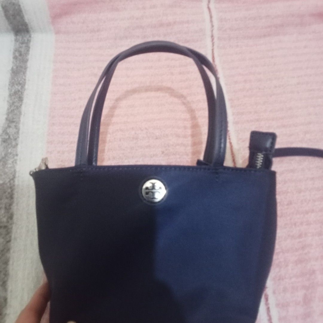Tory Burch Mini Tote Bag (Category: Luxury Bags & Wallets) located in Manila. Submitted by marijoyce01 (Listing ID 1432552940, Image 1). Description: - Tory Burch mini tote bag in navy blue - Top handle and detachable shoulder strap - Secure zipper closure - Features the iconic Tory Burch logo - Interior lined with matching blue fabric.