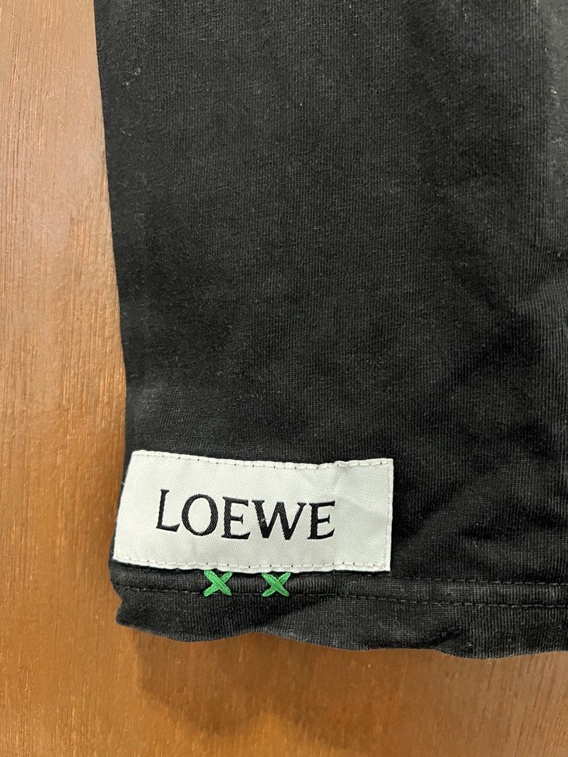 Loewe Black T-shirt (Category: Tshirts & Polo Shirts ) located in Meycauayan. Submitted by 3fold (Listing ID 1432699572, Image 2). Description: - Black Loewe t-shirt - Features the Loewe logo on the front - Additional logo detail at the back of the neck - Crew neck design - Short sleeves - Relaxed fit - Includes a small tag at the bottom.