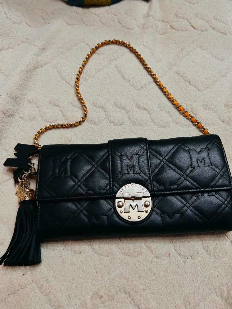Metrocity Black Quilted Chain Bag (Category: Luxury Bags & Wallets) located in Batangas. Submitted by selahs-closet (Listing ID 1432712253, Image 1). Description: - Metrocity black quilted handbag - Gold chain strap with orange accents - Flap closure with metallic logo - Includes a tassel charm - Diamond-stitched pattern.