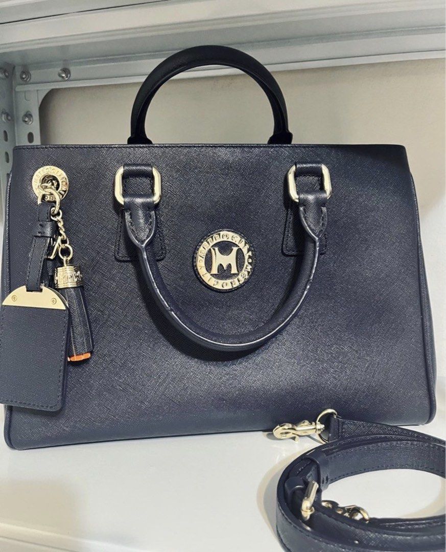 Metrocity Navy Blue Two way Handbag with Shoulder Strap (Category: Shoulder Bags) located in Quezon City. Submitted by whengaloolu (Listing ID 1432687527, Image 1). Description: - Metrocity navy blue handbag - Gold-tone hardware - Top handle and detachable shoulder strap - Matching tassel and tag included - Multiple interior compartments with zipper closure - Structured shape and textured finish - Comes with dust bag.