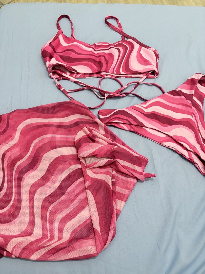 SHEIN Swim Bikini Set with Sarong (Category: Bikinis & Swimsuits) located in Muntinlupa City. Submitted by closetfinds_ph_952 (Listing ID 1432737158, Image 2). Description: - SHEIN Bikini Set - Size: Medium - Includes: Top, Bottom, and Sarong - Design: Pink wave pattern - Top: Adjustable straps, wrap-around tie - Bottom: High-cut style - Sarong: Can be tied around the waist.