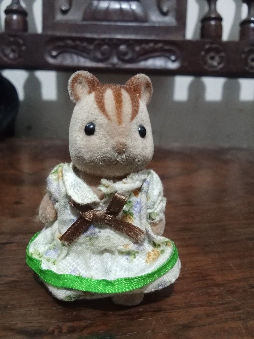 Sylvanian Families Chipmunk Figure (Category: Figurines & Statues) located in Bocaue. Submitted by marajapansurplus (Listing ID 1432639455, Image 1). Description: Adorable Sylvanian Families chipmunk figure is wearing a floral dress with a green trim and a brown bow. It has a fluffy tail and small feet..