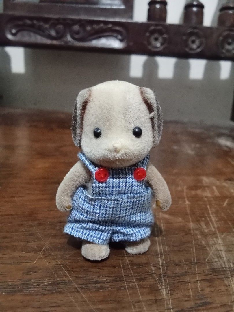 Sylvanian Families Dog Figure (Category: Figurines & Statues) located in Bocaue. Submitted by marajapansurplus (Listing ID 1432601510, Image 1). Description: - Adorable Sylvanian Families dog figure - Features blue overalls with red buttons - Light brown body with darker brown ears - Fluffy tail - Small and well-made - Perfect for collectors or play.