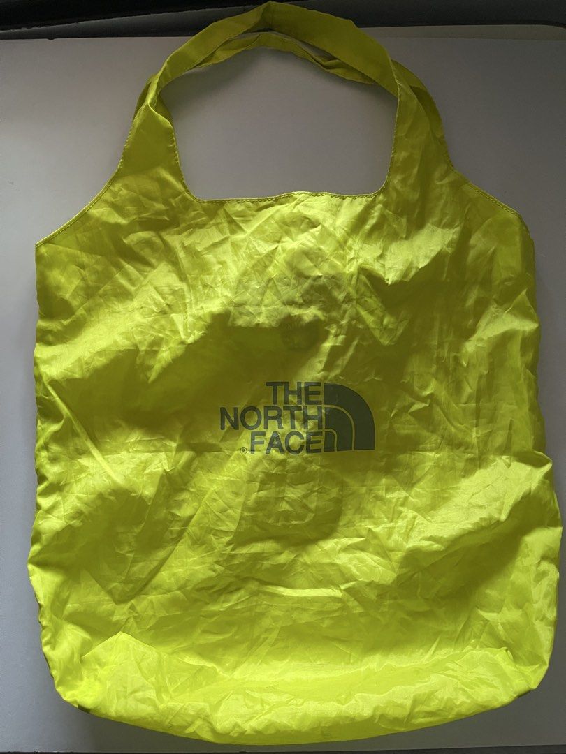 The North Face Packable Shopping Bag Eco Bag (Category: Tote Bags) located in Cavite. Submitted by abellu (Listing ID 1432634136, Image 2). Description: - The North Face shopping bag - Bright yellow color - Folds into a compact pouch - Gray zipper closure - Features a small red brand tag - Includes a carrying loop - Displays brand logo and graphic when unfolded.