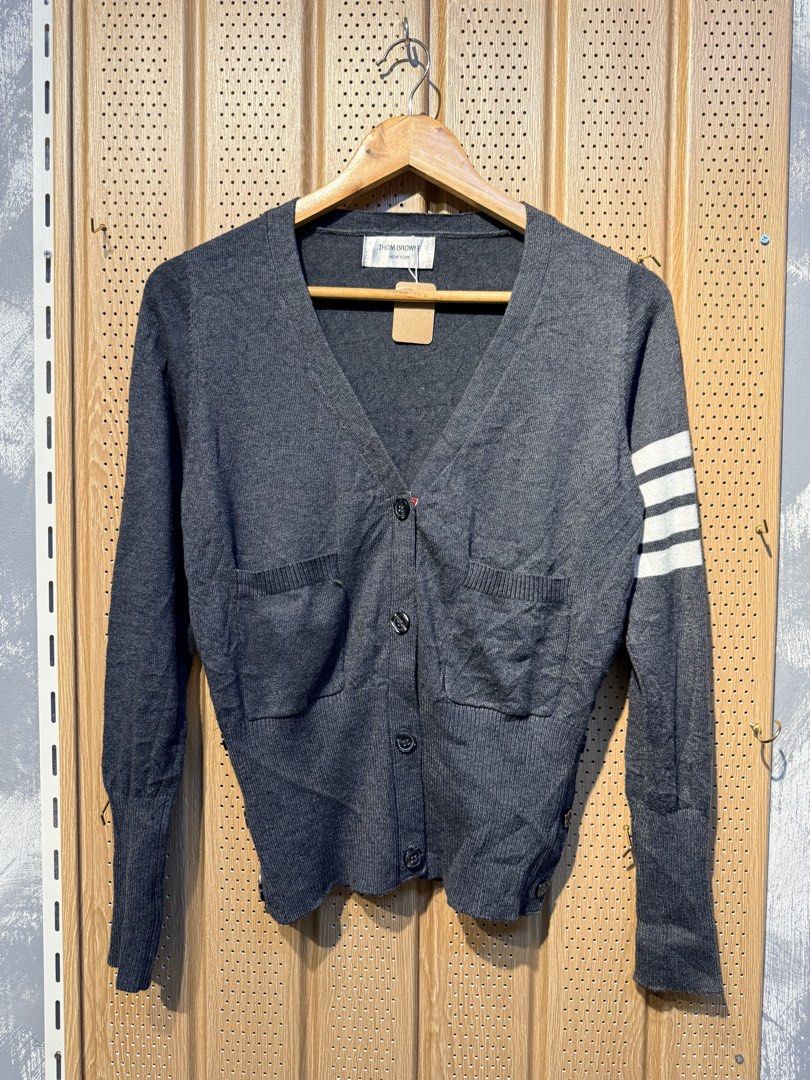 Thom Browne Grey Cardigan (Category: Luxury Apparel) located in Santiago. Submitted by twicebutnice03 (Listing ID 1432611993, Image 1). Description: - Thom Browne grey cardigan - V-neck design - Button-down closure - Two front pockets - Signature white stripes on left sleeve - Cuffs with red, white, and blue accents - Brand label visible Size & Dimes:MEDIUM-LARGE 18”23.