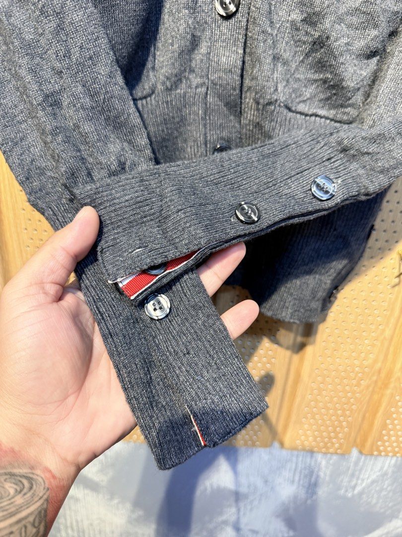 Thom Browne Grey Cardigan (Category: Luxury Apparel) located in Santiago. Submitted by twicebutnice03 (Listing ID 1432611993, Image 3). Description: - Thom Browne grey cardigan - V-neck design - Button-down closure - Two front pockets - Signature white stripes on left sleeve - Cuffs with red, white, and blue accents - Brand label visible Size & Dimes:MEDIUM-LARGE 18”23.