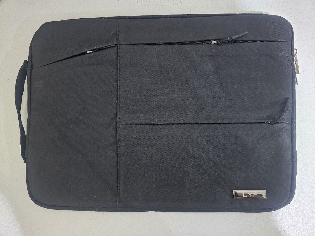 Black Laptop Sleeve with Handle (Category: Laptop Bags & Sleeves) located in Marilao. Submitted by ____jnsk (Listing ID 1432974310, Image 1). Description: - Black laptop sleeve - Features a handle for easy carrying - Multiple pockets for storage - Zipper closure for security - Silver logo detail - Interior lined with light grey fabric - Protects laptop from scratches and minor impacts.