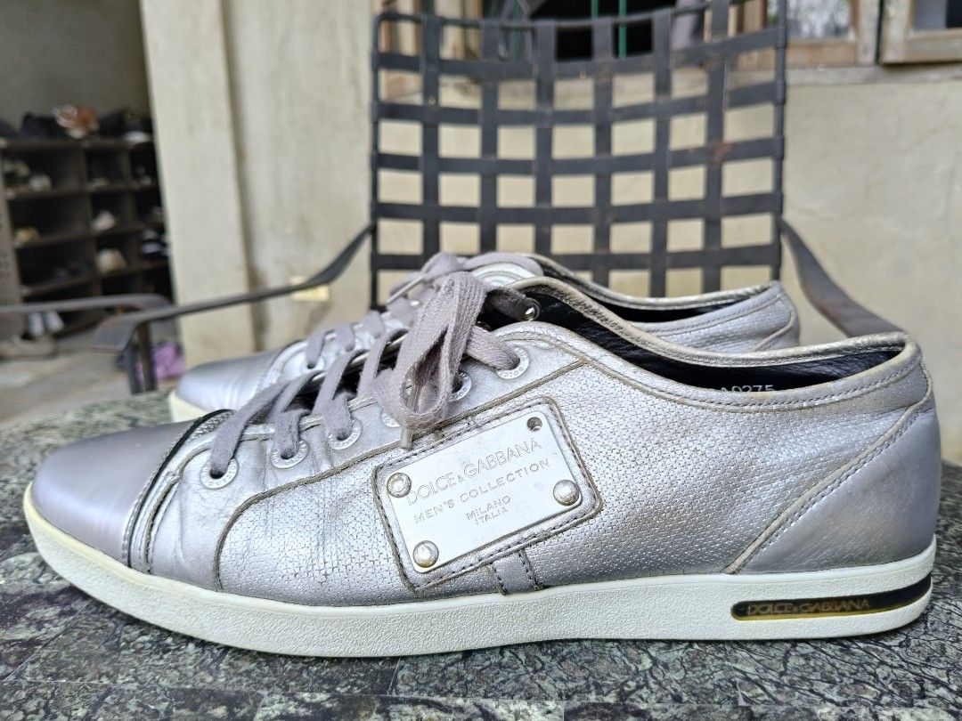 Dolce & Gabbana Sneakers (Category: Sneakers) located in Tagbilaran City. Submitted by johnmcee (Listing ID 1432865986, Image 1). Description: Dolce & Gabbana silver sneakers size on tag 9.5. best fit US9.5-10 - Leather upper - Perforated design on sides - Metal plate on tongue with brand name and "Men's Collection" - Dolce & Gabbana logo on soles - Grey laces - Low-top design issue: one missing screw on the side..