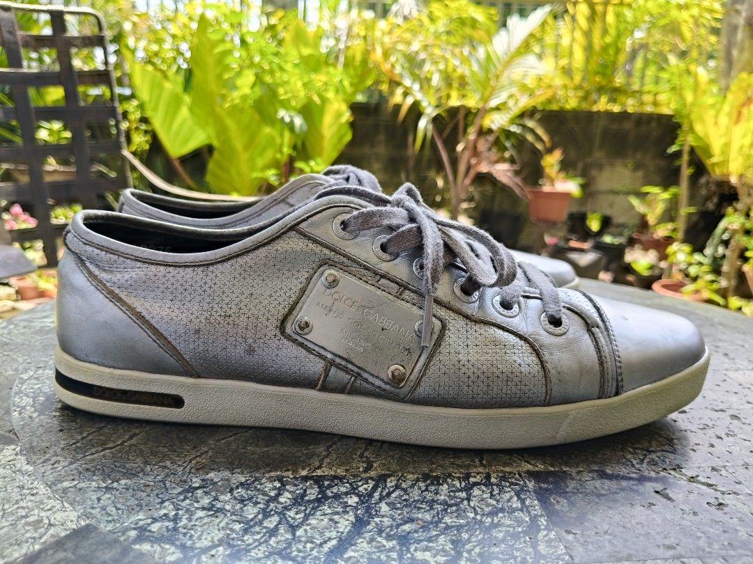 Dolce & Gabbana Sneakers (Category: Sneakers) located in Tagbilaran City. Submitted by johnmcee (Listing ID 1432865986, Image 3). Description: Dolce & Gabbana silver sneakers size on tag 9.5. best fit US9.5-10 - Leather upper - Perforated design on sides - Metal plate on tongue with brand name and "Men's Collection" - Dolce & Gabbana logo on soles - Grey laces - Low-top design issue: one missing screw on the side..
