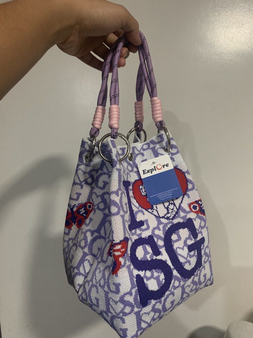 Explore I SG Handbag (Category: Tote Bags) located in Quezon City. Submitted by 47thclothing (Listing ID 1432914680, Image 1). Description: - Unique bucket bag design - Features "I SG" letters and heart patterns - Color scheme: White and purple - Handle accents: Pink and purple - Includes "Explore" tag.