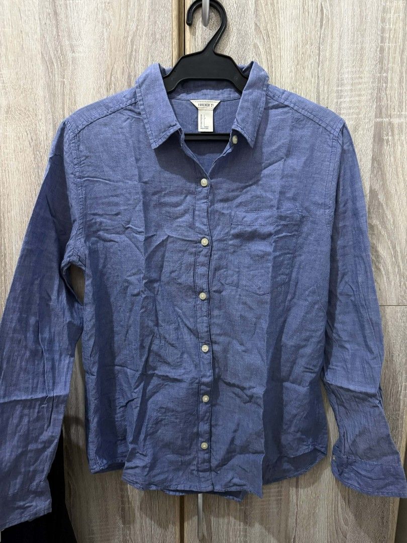 Forever 21 Blue Long Sleeve Shirt (Category: Longsleeves) located in Cavite. Submitted by ahlecz13 (Listing ID 1432951388, Image 2). Description: - Forever 21 blue long sleeve shirt - Button-down front - Chest pocket - Collared neckline - Classic design - Lightweight fabric - Size tag visible in photos.