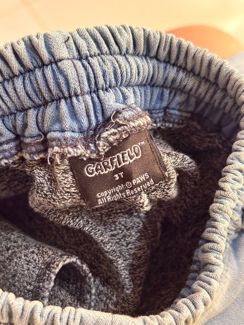 Garfield 3T Denim Jogger Pants (Category: Babies & Kids Fashion) located in Urdaneta. Submitted by glamduck (Listing ID 1432872385, Image 3). Description: - Brand: Garfield - Size: 3T - Style: Denim jogger pants - Features: Elastic waistband with drawstring - Pockets: Two front pockets, one back pocket - Detail: Small red "G" patch on front.