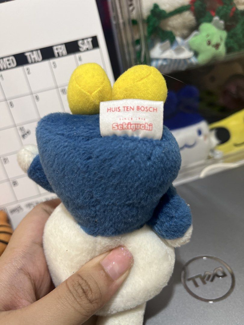 Miffy Plush Toy Keychain by Sekiguchi (Category: Plushies & Soft Toys) located in Candelaria. Submitted by wishizen (Listing ID 1432928133, Image 2). Description: - Adorable Miffy plush toy - Features a blue outfit and red bow tie - Includes yellow feet - Has a label on the front - Tag on the back reads "Huis Ten Bosch" and "Sekiguchi Since 1918" .